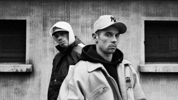 A Black and White Picture with 2 Man Wearing Jackets and Caps